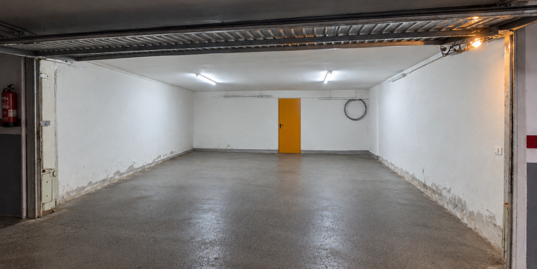Garaje vacío con puerta amarilla y luces frías