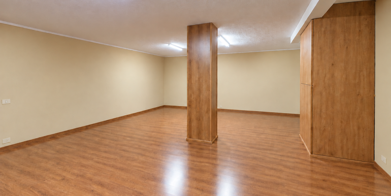 Sala amplia vacía con columna de madera y luz fluorescente